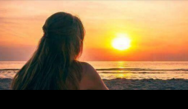 Silueta d'una dona d'esquena observant una posta de sol 